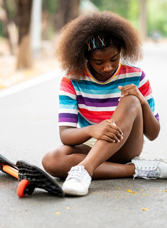 Skateboarder sitting on the ground and looking at knee